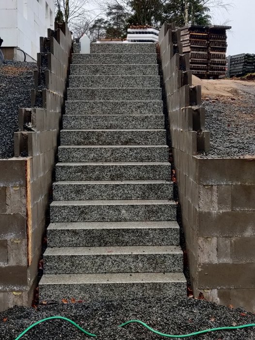 Granittrappa mellan betongmurar på en byggarbetsplats.