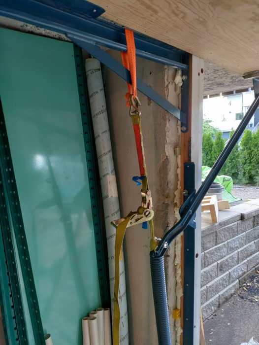 En garageportsfjäder som dras upp med spännband fastsatt vid en vinkelfäste i ett byggprojekt.