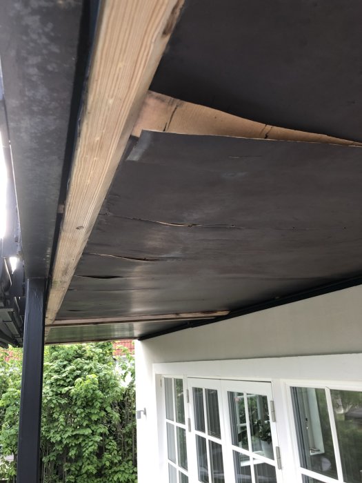 Undersidan av en balkong med vattenskadad plywood och synliga stålkonstruktioner.
