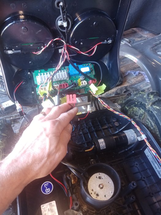 Inre delar av en Stiga Autoclip robotgräsklippare med synligt kretskort och någons hand.