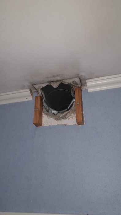 Öppning i tak med synligt ventilationsschakt och stödträ utan täckande låda.