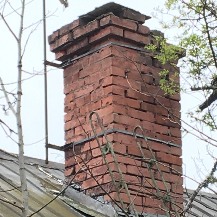 Sliten tegelskorsten ovanför ett tak som behöver ommurning.