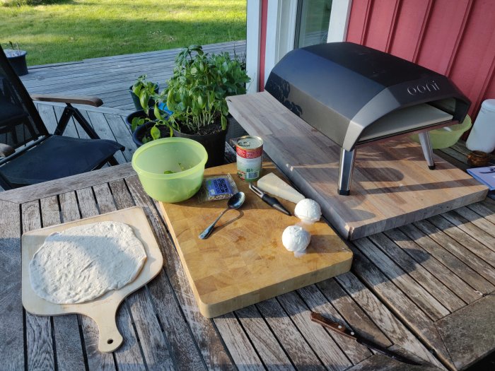 Ooni Koda 12 pizzaugn på trädäck med pizzadeg, mozzarella och tomatsås redo för matlagning.