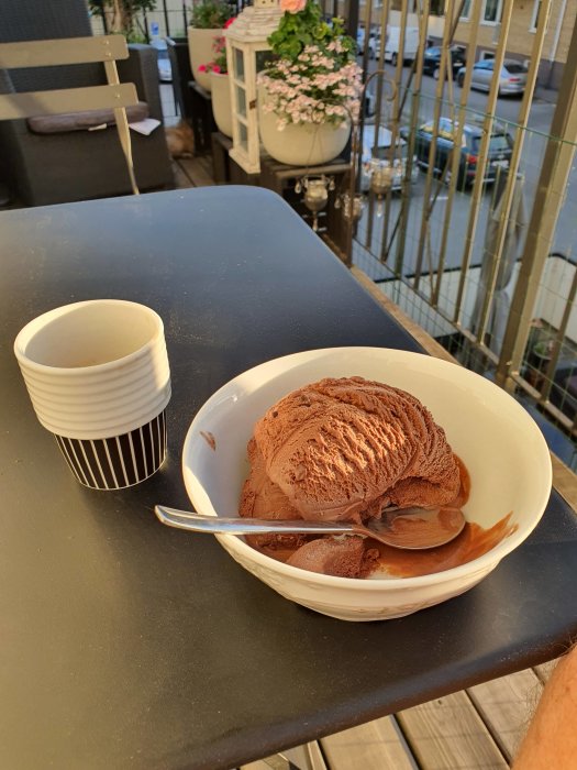 En espresso och skål med chokladglass på ett bord på balkongen.