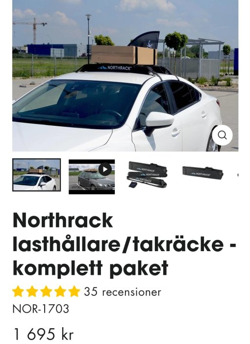 Vit bil med ett Northrack takräcke monterat på taket och en kartong fastspänd ovanpå, i en stadsinställning.