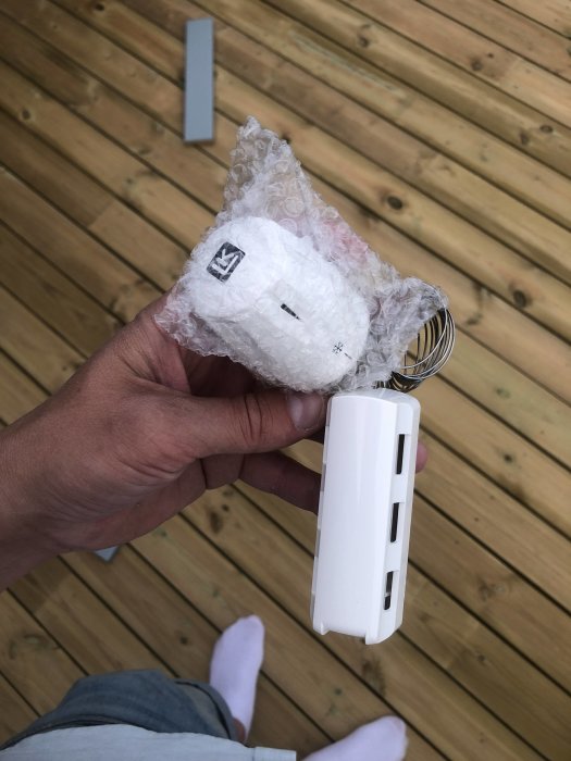 Hand håller en vit dörrvred med bubbelplast som är till övers efter renovering.