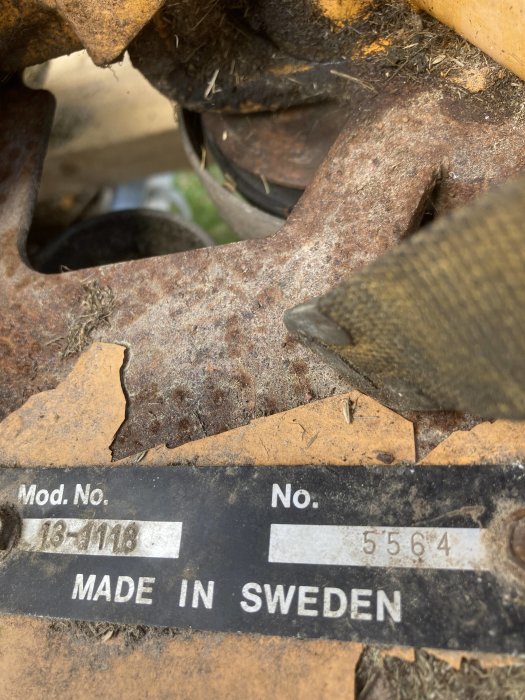 Närbild på en märkningsetikett som säger "Mod. No. 13-118, No. 5564, MADE IN SWEDEN" på en rostig metallkomponent.