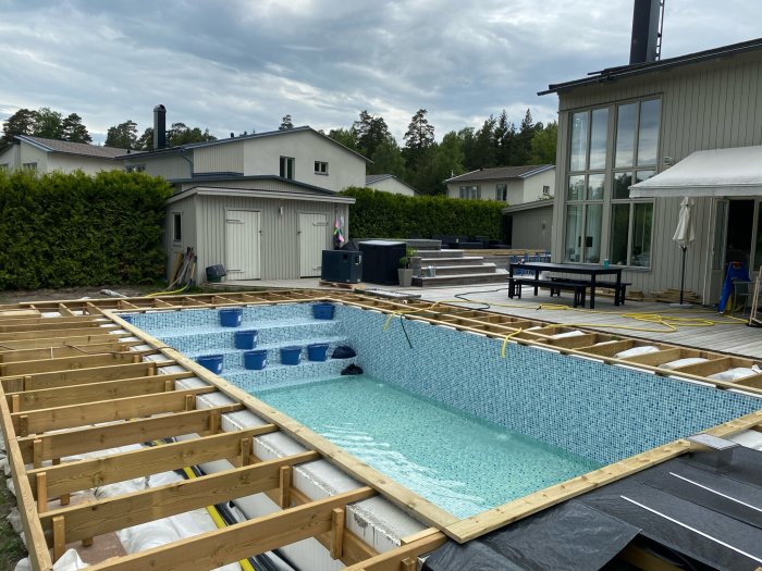 Backyard pool construction with liner installed and wooden framework for decking under progress.