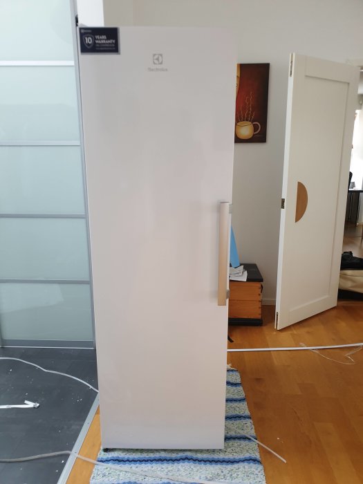 Electrolux frysskåp står i ett rum med fråga om att byta hängning på dörren.