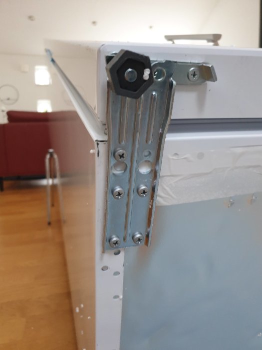 Nedre upphängning för dörr på Electrolux frysskåp som tyder på att en "pinne" kan behöva flyttas för att ändra hängningen.