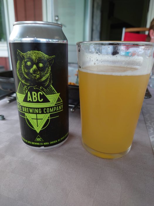 Burk med DIPA-öl från Apex Brewing Company och ett glas med hazy öl bredvid på ett bord.