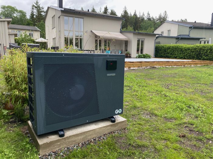 Värmepump vid trädgård under uppbyggnad av poolområde med ny trall i bakgrunden.