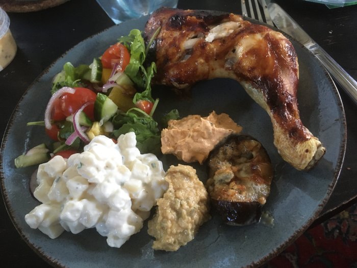 Grillat kycklingben med potatissallad, hummus, färskostblandning, sallad och aubergine med gorgonzola på en tallrik.