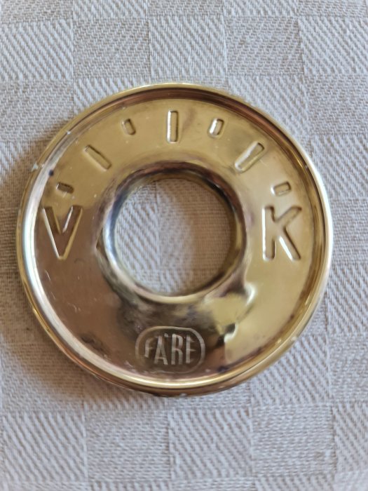 Gammaldags guldtonat termostatvred märkt "IARE" på texturerad bakgrund.