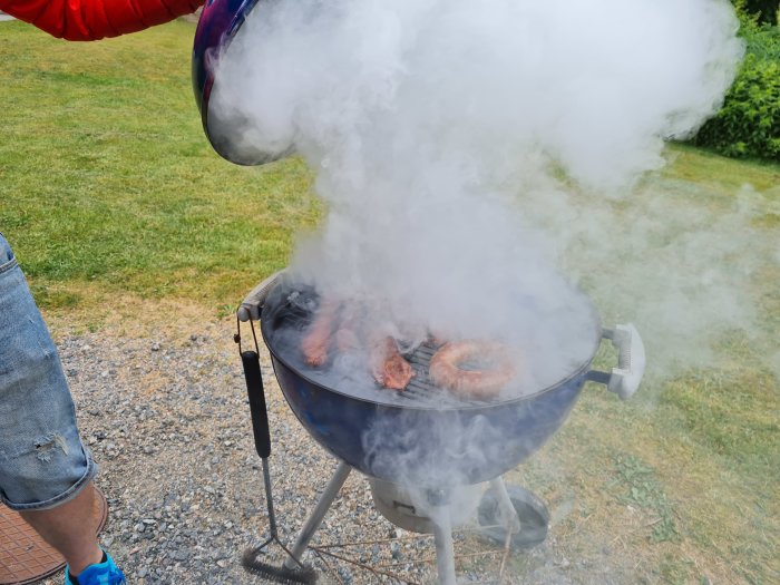 Bacon och en Salsiccia på en rökig kolgrill utomhus.