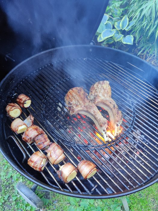 Grillat kött och grönsaker lindade med bacon på en kolgrill, med synliga lågor.
