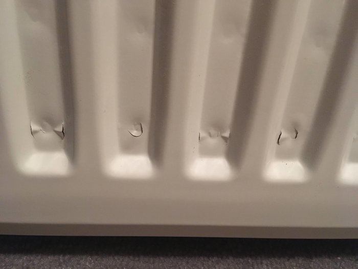 Radiatormålning med flagande färg och synliga skador.