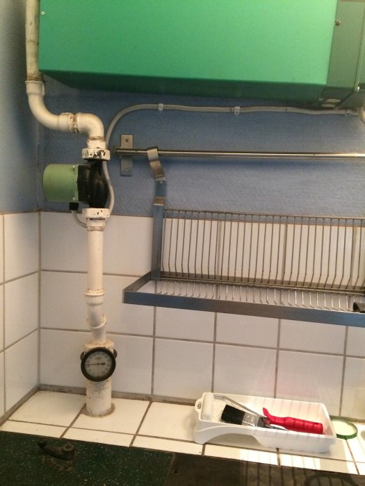 VVS-installation i badrum med rör, mätare och målarverktyg på golvet.