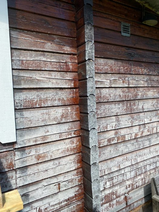 Trävägg utomhus med synliga regnskador, brun färg övergår i grå efter regnet.