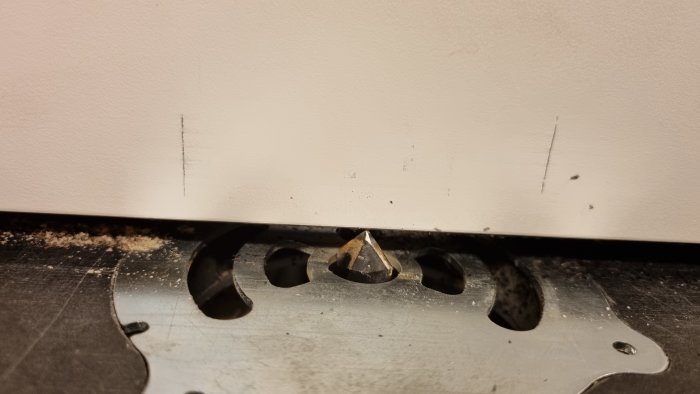 Närbild av en klinga på ett verktyg med spån och märken på ytan som tyder på användning i bearbetning.