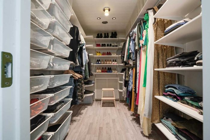 Välorganiserad klädkammare med skor, hyllor med kläder och lådor.