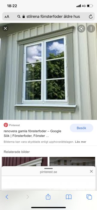 Fönster med stilrena vita foder och grönt träd reflekterat i glaset mot en ljus fasad.