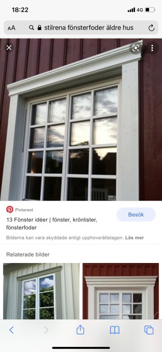 Stilrena vita fönsterfoder kring ett klassiskt fönster på en äldre husfasad med mörkröda paneler.