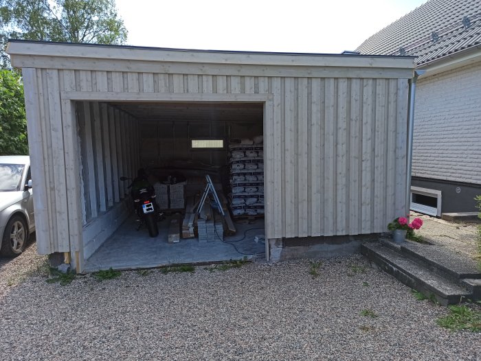 Garage under renovering, med ny fasadpanel och råspont, före montering av garageport.