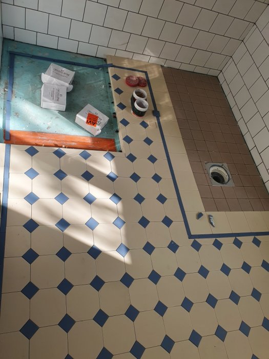 Renoveringsprojekt av badrum med blå-vit kakel, byggmaterial på golvet och duschplats.