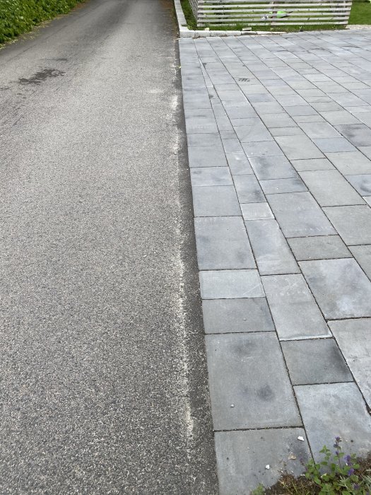 Välbevarade grå trottoarplattor längs med en asfalterad väg ett år efter läggning.