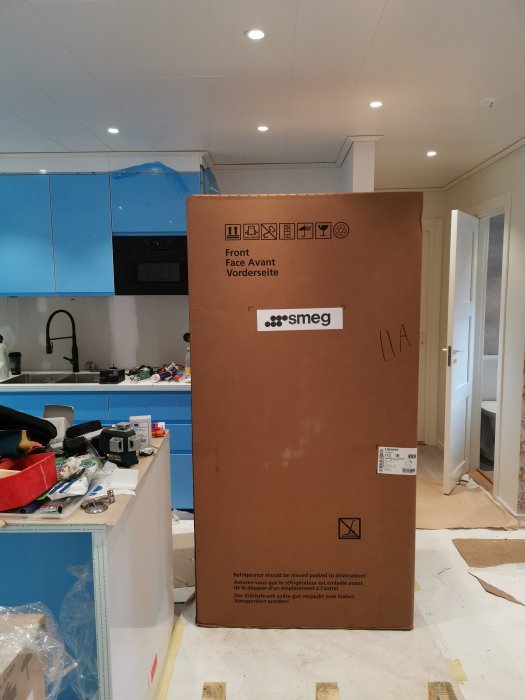 Stort kartongförpackat Smeg-kylskåp mitt i pågående köksrenovering.