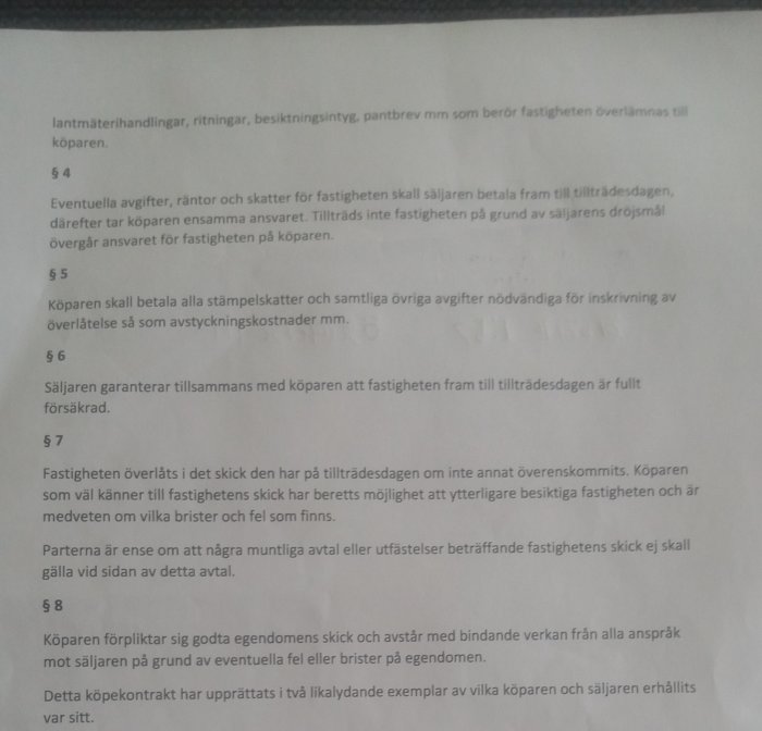 En närbild av ett köpekontrakt med text om skyldigheter och ansvar i samband med fastighetsöverlåtelse.