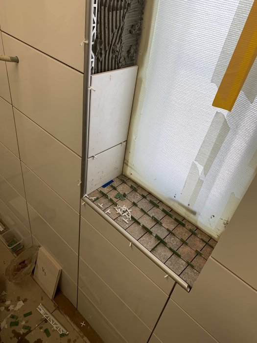 Nyinstallerat kakel på vägg och klinkers på fönsterbräda i ett renoveringsprojekt.