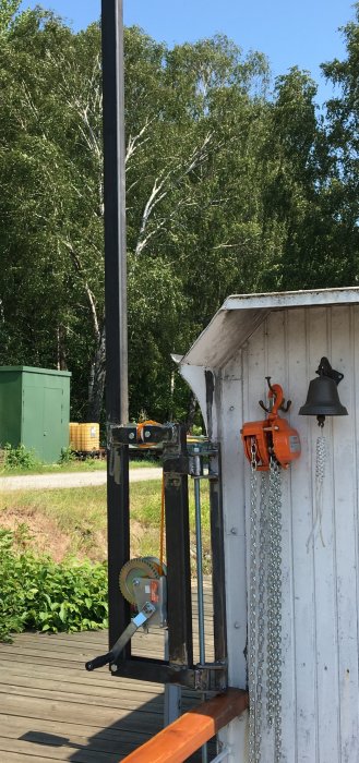 Svetsade metallkonstruktioner och kättingblock för att lyfta tung last, vid ett träskjul utomhus.