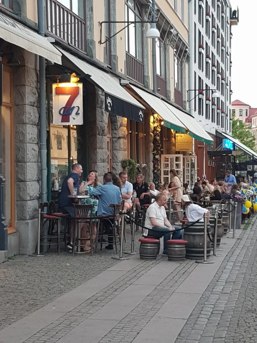 Uteservering i Göteborg kvällstid, människor sitter vid bord, gatutsikt med uteserveringen "sjuan".