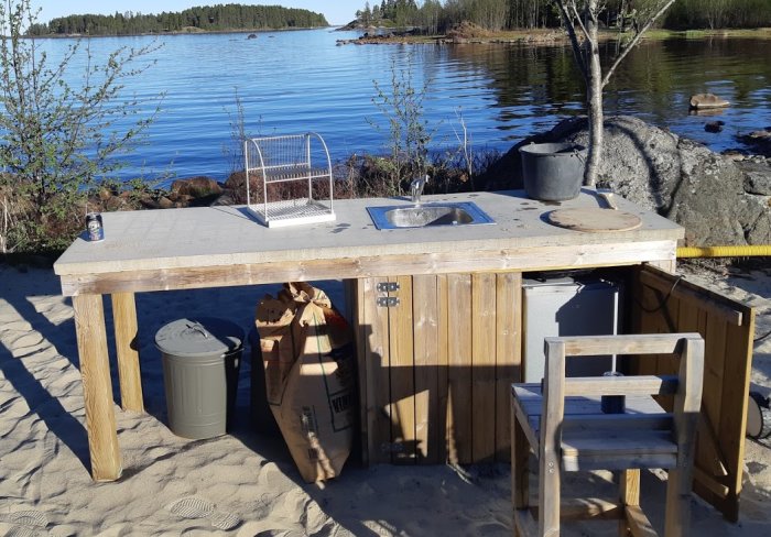Enkelt utekök med diskho och arbetsyta vid strandkanten.