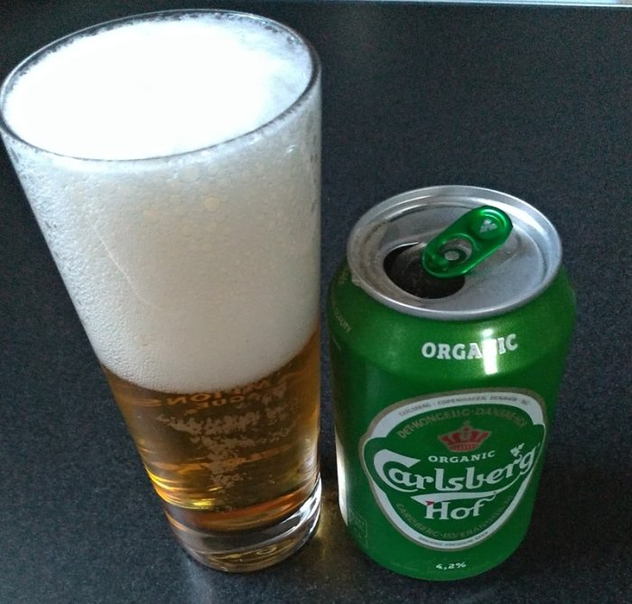 Glas med öl och en öppen burk Carlsberg Hof på en arbetsbänk.