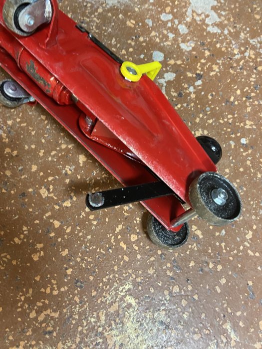 Röd verktygsvagn med synlig slitage på ett fläckigt golv.