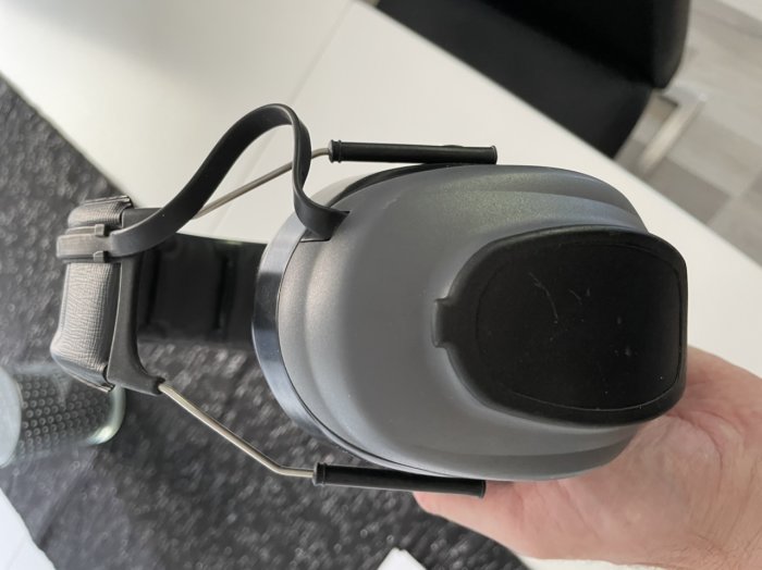 Hand håller Peltor Worktunes hörselskydd med display, linjeingång, utan Bluetooth, i mycket fint skick.