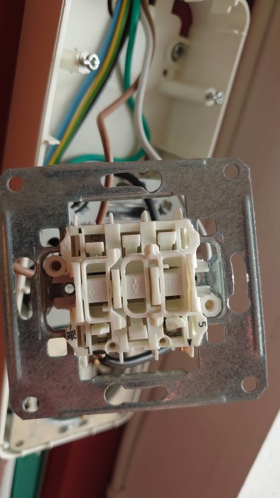 Eluttag under installation med osäkrade kablar och vit plastbit som ska tas bort.
