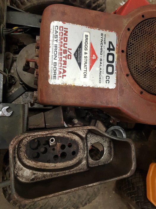 Öppen luftbox till en Briggs & Stratton 400CC motor på en åkgräsklippare utan luftfilter, smuts och damm synligt.