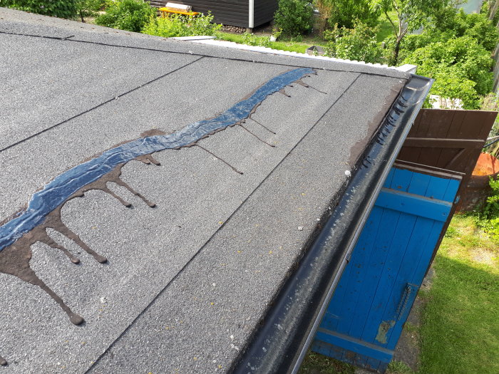 Sprucket takpapp på stugtak med lagning av takmassa längs en våd och vid takfoten.