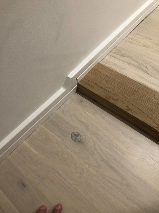 Installation av golvsockel vid dörrtröskel och laminatgolv, hantverk i hemmet.