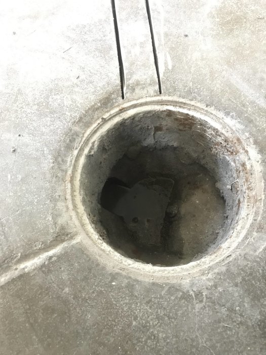 Vy inuti ett avloppsrör under ett galler som visar sidöppning och potentiellt vattenlås.