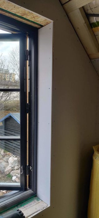 Närbild på en nyinstallerad fönsterram med OSB- och gipsskivor, inifrån en byggnad under renovering.