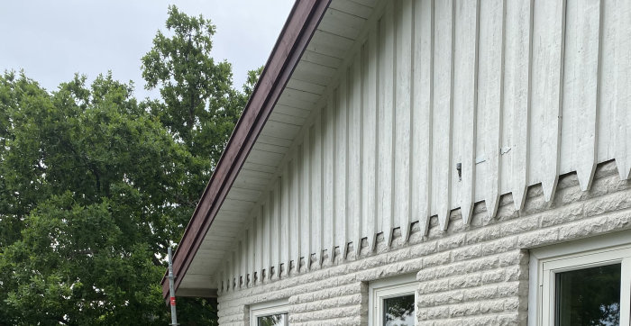 Vitmålat mexitegelhus med karakteristiska spetsiga taggar längs takkanten på gaveln.
