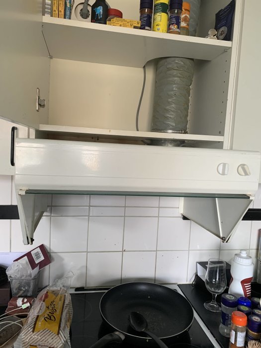 Kökshuva utan synliga skruvar monterad under vit köksskåp över spisen, med förvirrad användare.