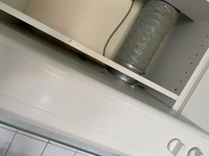 Översikt av öppen köksskåpsunderdel som exponerar inuti och baksidan av en odefinierad kåpa utan synliga skruvar.