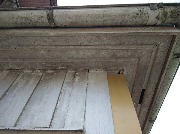 Före underhåll bild på smutsigt hus med träpanel och hängränna, behöver rengöring och målning.