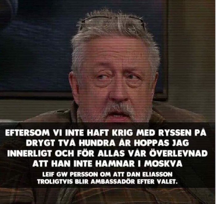 Man med silverhår och skägg uttrycker en kommentar om en person som potentiell ambassadör, citerad i en textremsa.